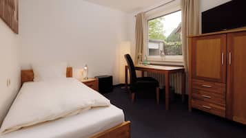 A hotel room with a bed, a desk, a chair, a TV, and a wardrobe.
