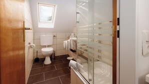 Ein Badezimmer mit Toilette, Bidet und einer Duschkabine aus Glas.