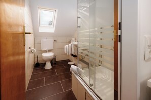 Een badkamer met toilet, bidet en een douchecabine met glazen wanden.
