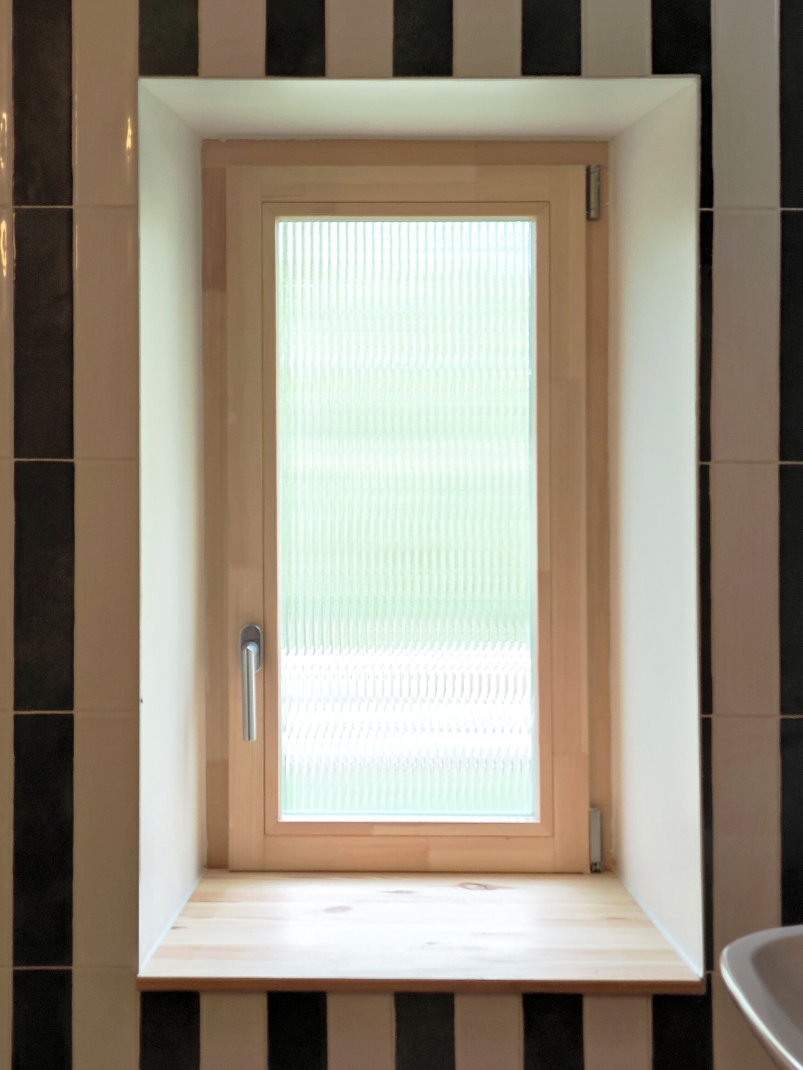 A bathroom with a wooden door, a bench, and a tiled wall.