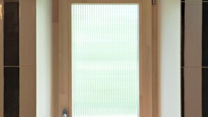 Ein Badezimmer mit Holztür, einer Sitzbank und einer gefliesten Wand.