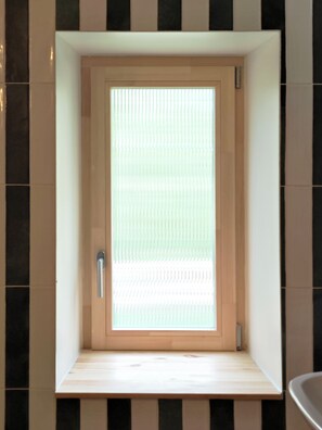Een badkamer met een houten deur, een bankje en een betegelde muur.