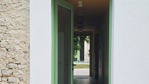 Ein Korridor mit einer grünen Tür, die zu einem fliesenbelagten Bereich führt.