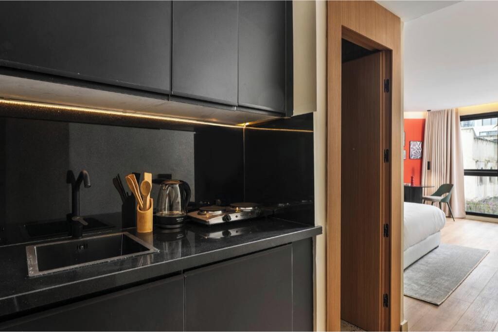 A modern kitchen with black cabinetry, a stainless steel sink, and a coffee maker.