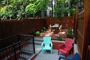 A fenced backyard with a patio area, outdoor furniture, and a wooden fence. - Brownstone Cove (New York)