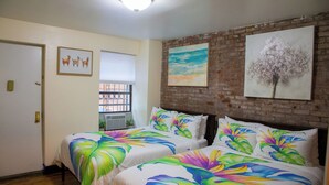 Ein Hotelzimmer mit zwei Betten, einer Ziegelwand und Bildern an der Wand.