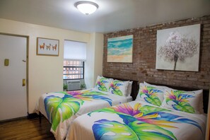 A hotel room with two beds, a brick wall, and artwork on the wall. - Brownstone Cove (New York)