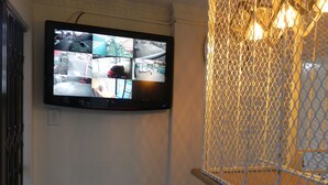 A security camera mounted on a wall, a window with a metal grid, and a marble-like surface below. - OZ Guest Villa (Johannesburg South)