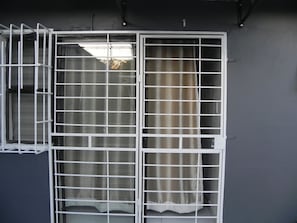 Ein Fenster mit einem Metallgittermuster, einem Vorhang und einer Wand mit einem Schild mit der Nummer 1.
