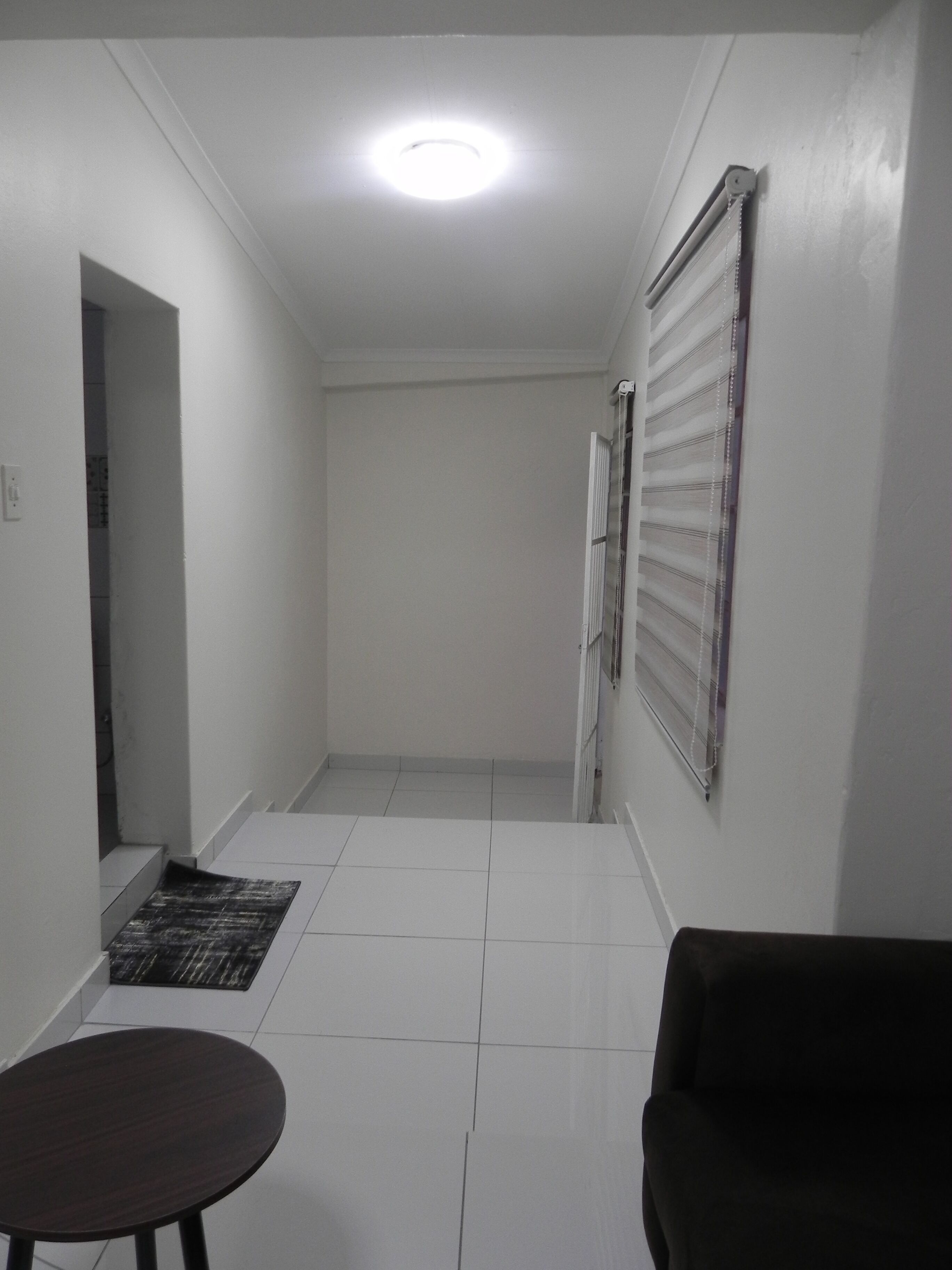 A hallway with a tiled floor, a round table, and a dark-colored sofa.