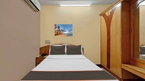 A hotel room with a bed, bedside table, lamp, wardrobe, and a wall-mounted picture. - Collection O Bannerghatta Road (Bengaluru)