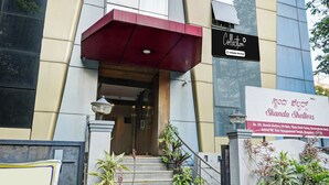 A building entrance with a staircase, a red awning, and a sign indicating 'Skanda Shelters'. - Collection O Bannerghatta Road (Bengaluru)