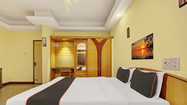A hotel room with a large bed, a desk, a chair, and a painting on the wall. - Collection O Bannerghatta Road (Bengaluru)