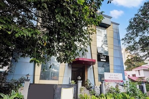 A modern building with a glass facade, a red awning, and a sign indicating 'Collection' and 'Skanda Shelters'.