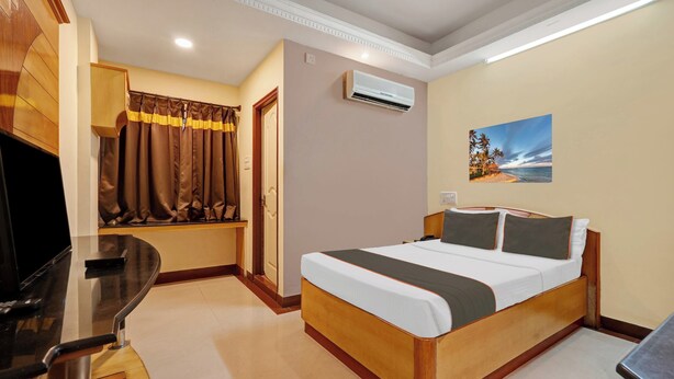 Habitación de hotel con cama, escritorio, televisión, aire acondicionado y un cuadro en la pared.