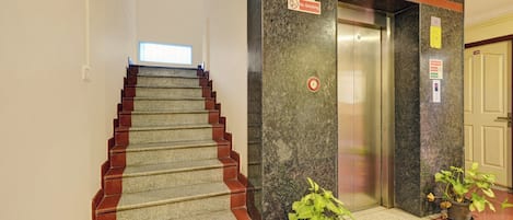 A hotel lobby with a staircase, an elevator, and a door marked with the number 108.