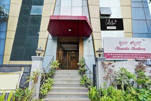 A building entrance with a staircase leading to a door, a red awning, and a signboard for Skanda Shelters. - Collection O Bannerghatta Road (Bengaluru)