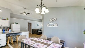 Eine moderne Küche mit Essbereich, ausgestattet mit einer zentralen Kochinsel, Pendelleuchten und einem Deckenventilator.