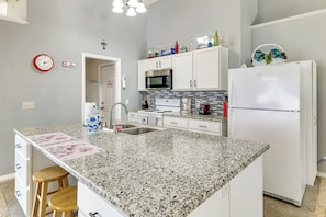 A kitchen with a granite countertop, white cabinets, a microwave, a stove, and a refrigerator. - Pool, Hot Tub & Kids' Play Area! Davenport Home (Davenport)