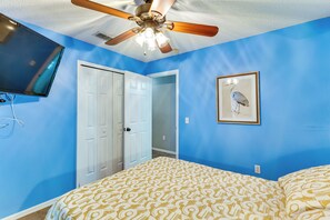 A bedroom with a ceiling fan, a bed with patterned bedding, a white door, and a framed picture on the wall. - Pool, Hot Tub & Kids' Play Area! Davenport Home (Davenport)