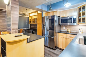 A modern kitchen with stainless steel appliances, wooden cabinets, and a central island. - Walkable Tempe Condo < 1 Mi to ASU Campus! (Tempe)