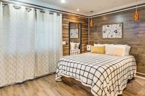 A bedroom with a bed, wooden flooring, a mirror, and a wall-mounted artwork. - Walkable Tempe Condo < 1 Mi to ASU Campus! (Tempe)