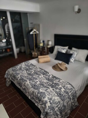 A neatly made bed with a patterned bedspread, pillows, and a hat on the bed. - Family home in an Alentejo village (Amieira Portel)