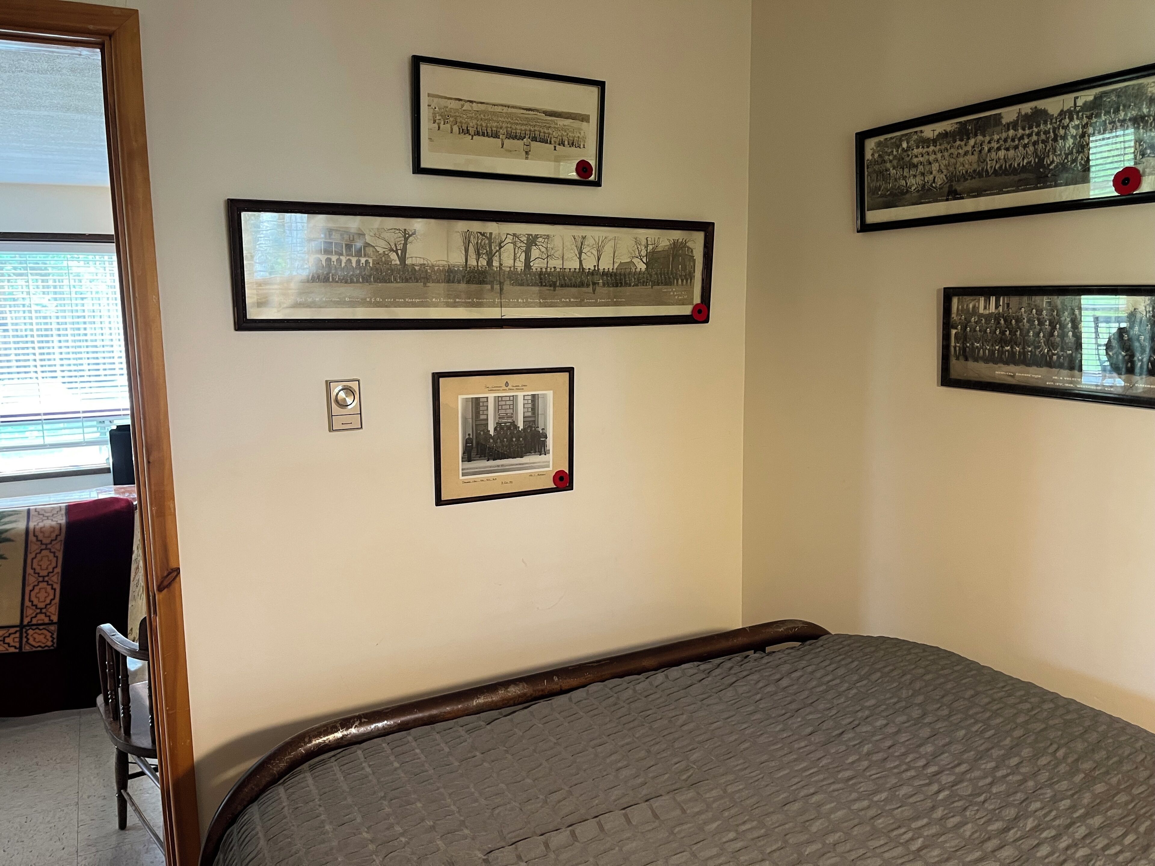 Una habitación con cama, fotografías enmarcadas en la pared, una ventana y una puerta.