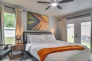 A bedroom with a bed, a nightstand, a lamp, a ceiling fan, and a view of the outdoors. - 4 Mi to Beach! Dual-unit Safety Harbor Retreat (Safety Harbor)