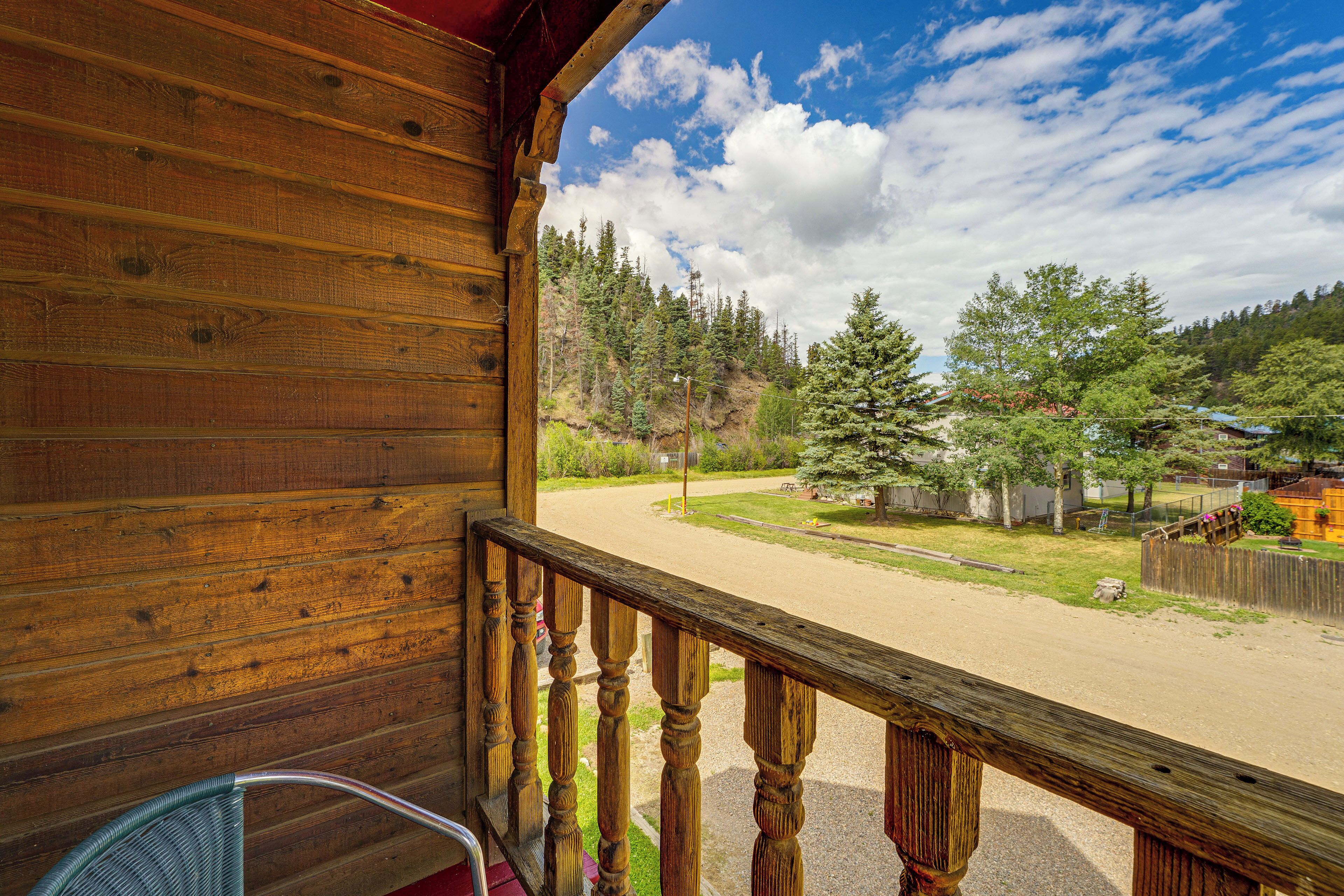 A wooden cabin with a porch overlooking a forested area.