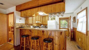 Una cocina con armarios de madera, una barra con taburetes y un microondas.