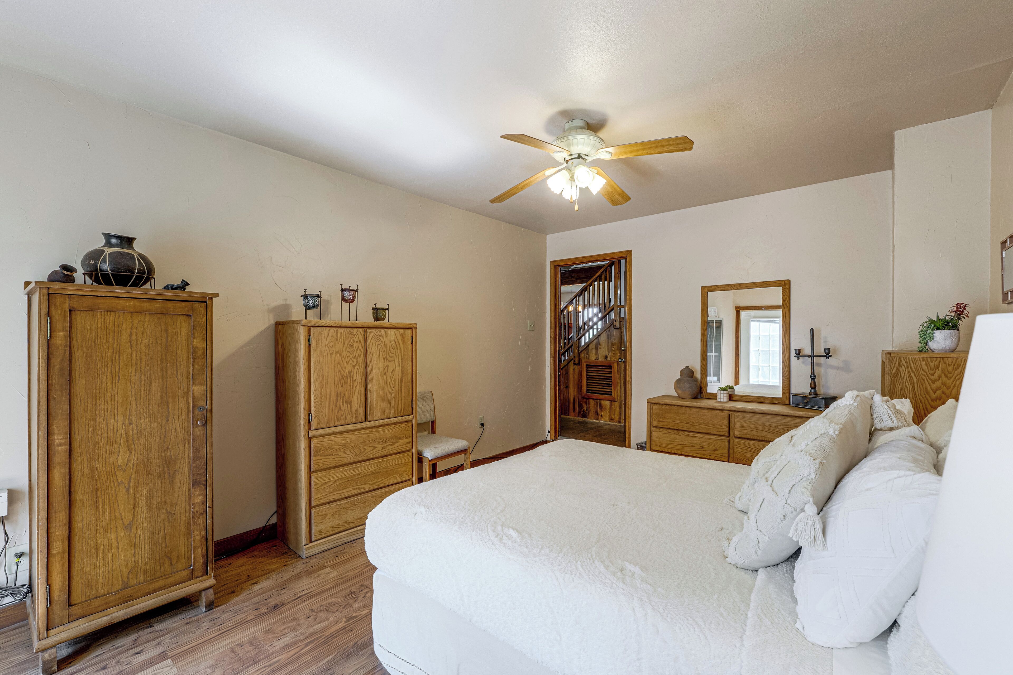 Un dormitorio con una cama grande, un armario de madera y un ventilador de techo.