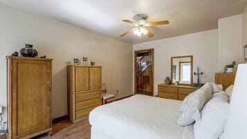 Un dormitorio con una cama grande, un armario de madera y un ventilador de techo.