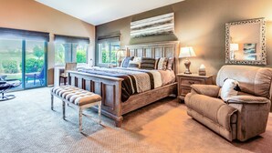 A bedroom with a large bed, a chair, a bench, a nightstand, and a mirror. - Work & Play in Indio: Golf Course Home w/ Patio (Indio)