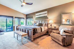 A bedroom with a large bed, a chair, a bench, a nightstand, and a mirror. - Work & Play in Indio: Golf Course Home w/ Patio (Indio)