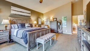 A bedroom with a large bed, bedside tables, a bench, a dresser, and a mirror. - Work & Play in Indio: Golf Course Home w/ Patio (Indio)