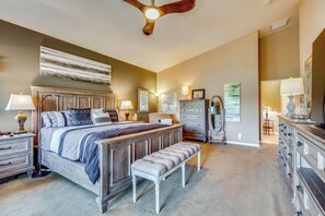A bedroom with a large bed, bedside tables, a bench, a dresser, and a mirror. - Work & Play in Indio: Golf Course Home w/ Patio (Indio)