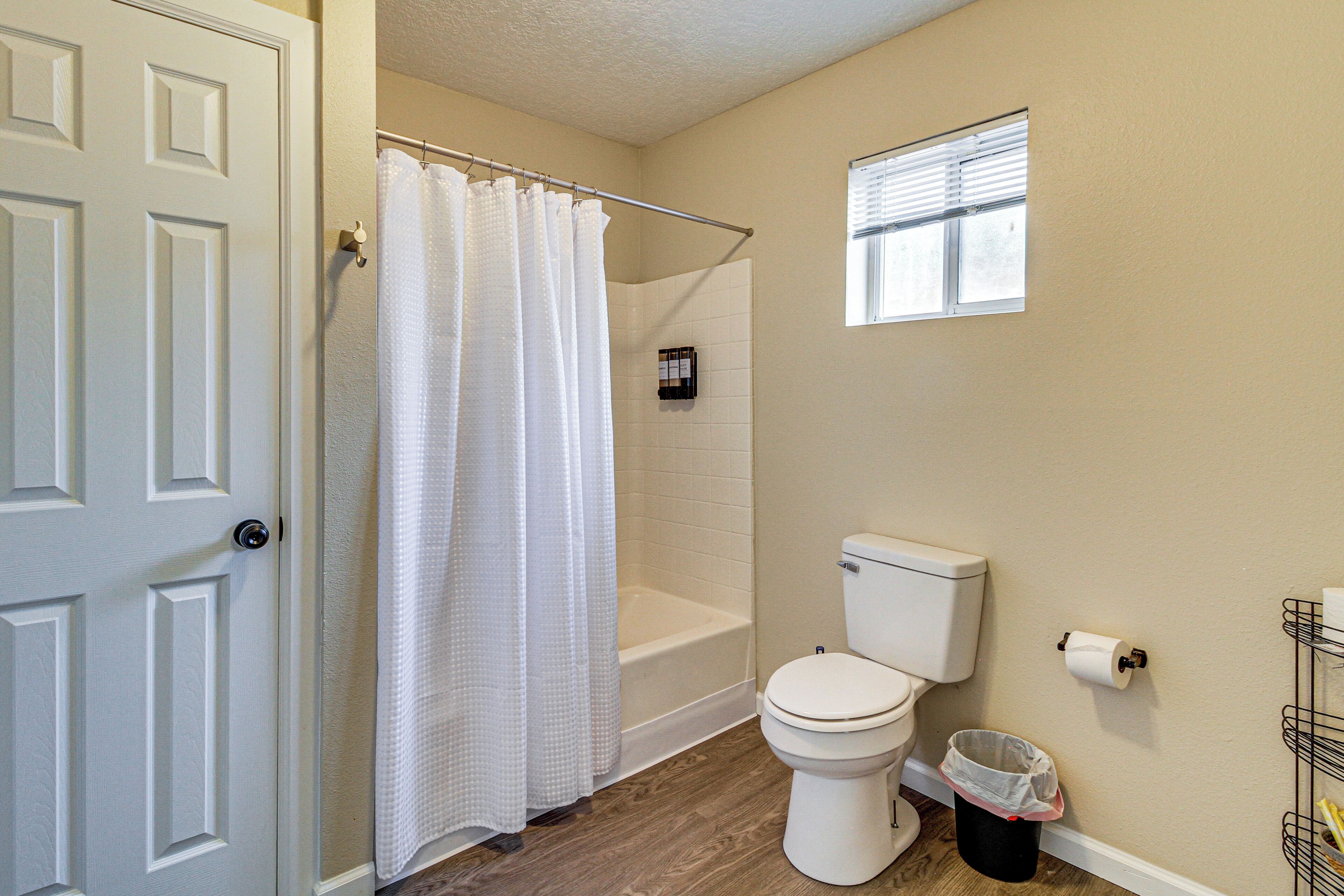 A bathroom with a toilet, a shower, and a window.