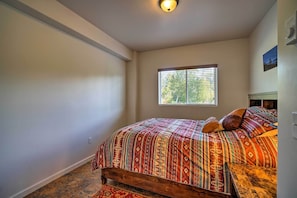 A bedroom with a wooden bed, a window with blinds, and a light fixture on the ceiling. - Steps to Fritz Creek! 2-unit Family Retreat (Homer)