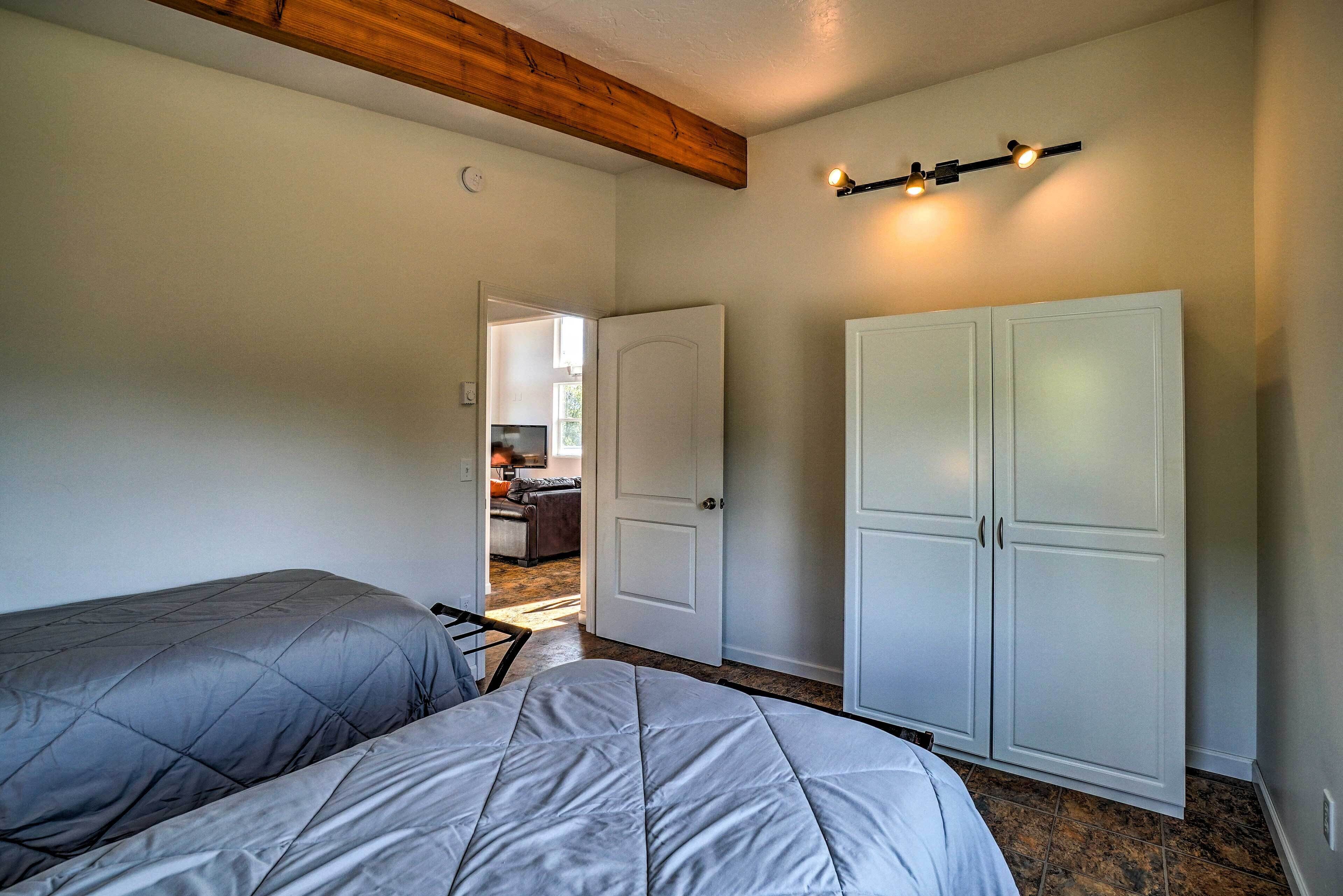 Un dormitorio con dos camas, un armario y una puerta que da a otra habitación.