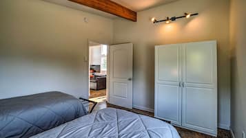 Un dormitorio con dos camas, un armario y una puerta que da a otra habitación.