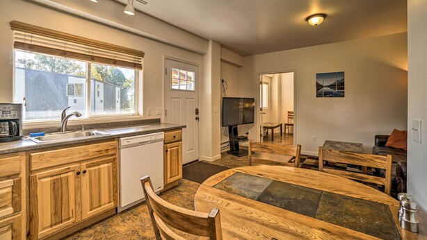 A modern kitchen with wooden cabinets, a large island, and a dining area with a table and chairs.