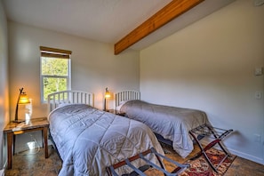 A bedroom with two beds, a window, a lamp, and a radiator.