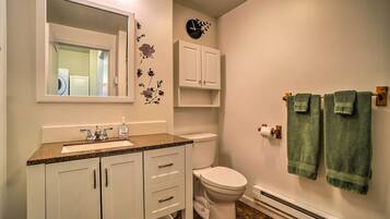 Une salle de bain équipée d’un lavabo, d’un miroir, de toilettes, d’un meuble de rangement et de serviettes.