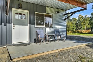 A building with a white door, a window, and a porch with two chairs and a table.