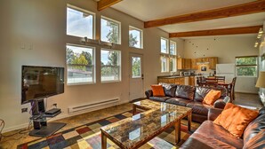 A spacious living area with a large flat-screen TV, leather sofas, and a colorful checkered carpet.