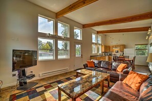 A spacious living area with a large flat-screen TV, leather sofas, and a colorful checkered carpet.