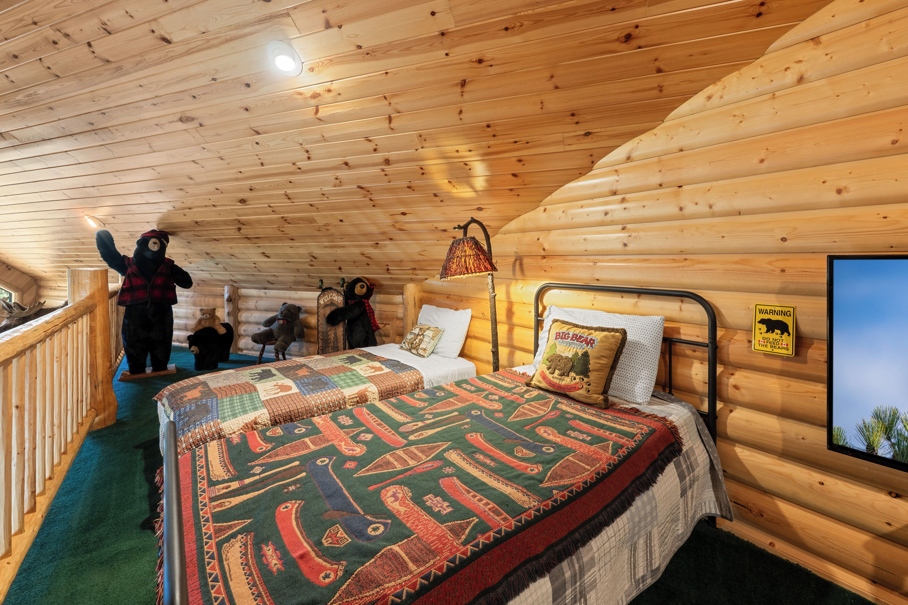 Une chambre dans une cabane en bois, avec un lit, des oreillers, une lampe et un panneau d’avertissement.