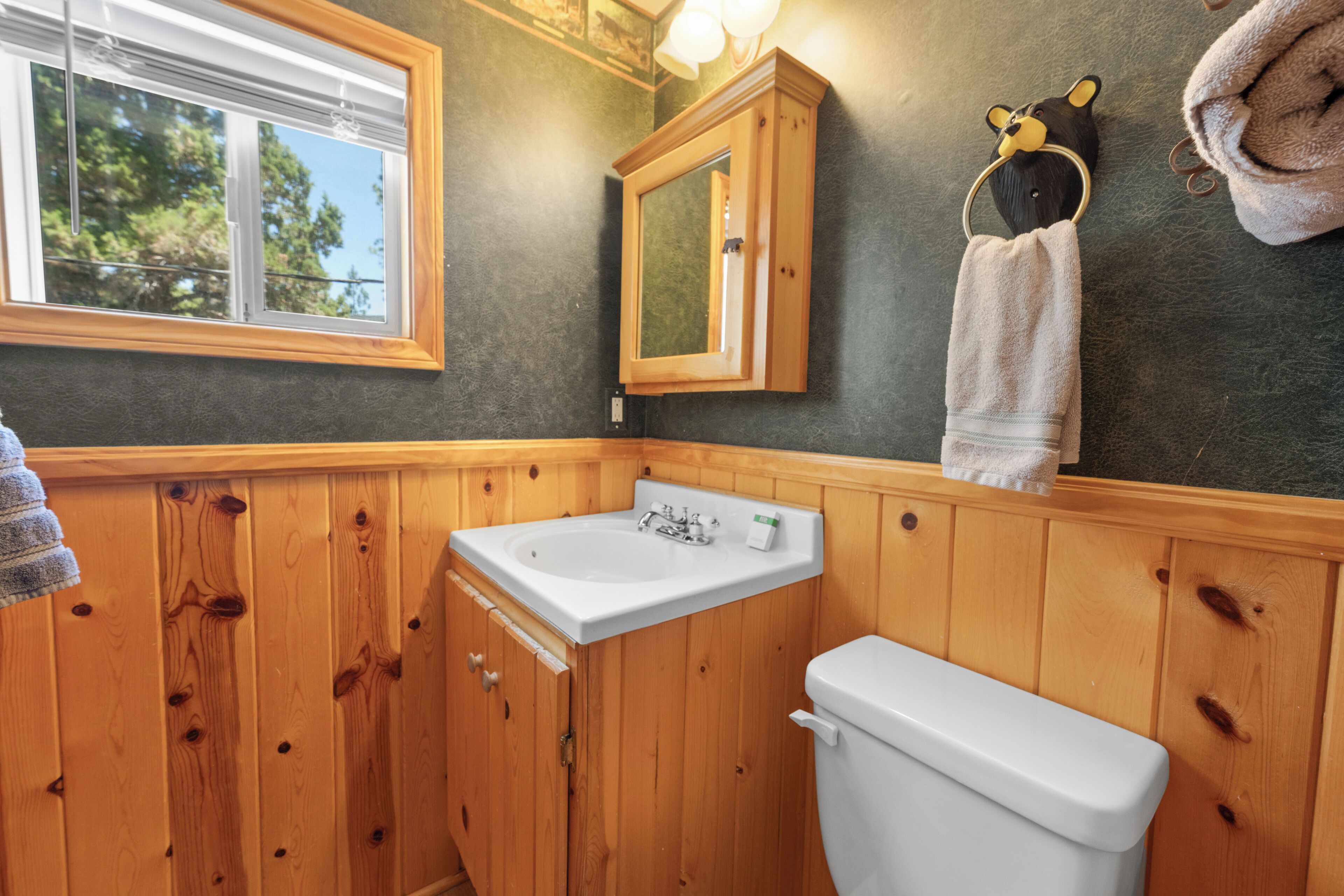 A bathroom with wooden paneling, a white sink, a mirror, and a towel rack.