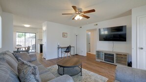 A spacious living room with a ceiling fan, a flat-screen TV, a dining area with a table and chairs, and a sofa set. - Walk to Med Center! Extended Wilmington Condo (Wilmington)